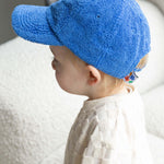 Child wearing a blue towel cap sitting on a textured surface