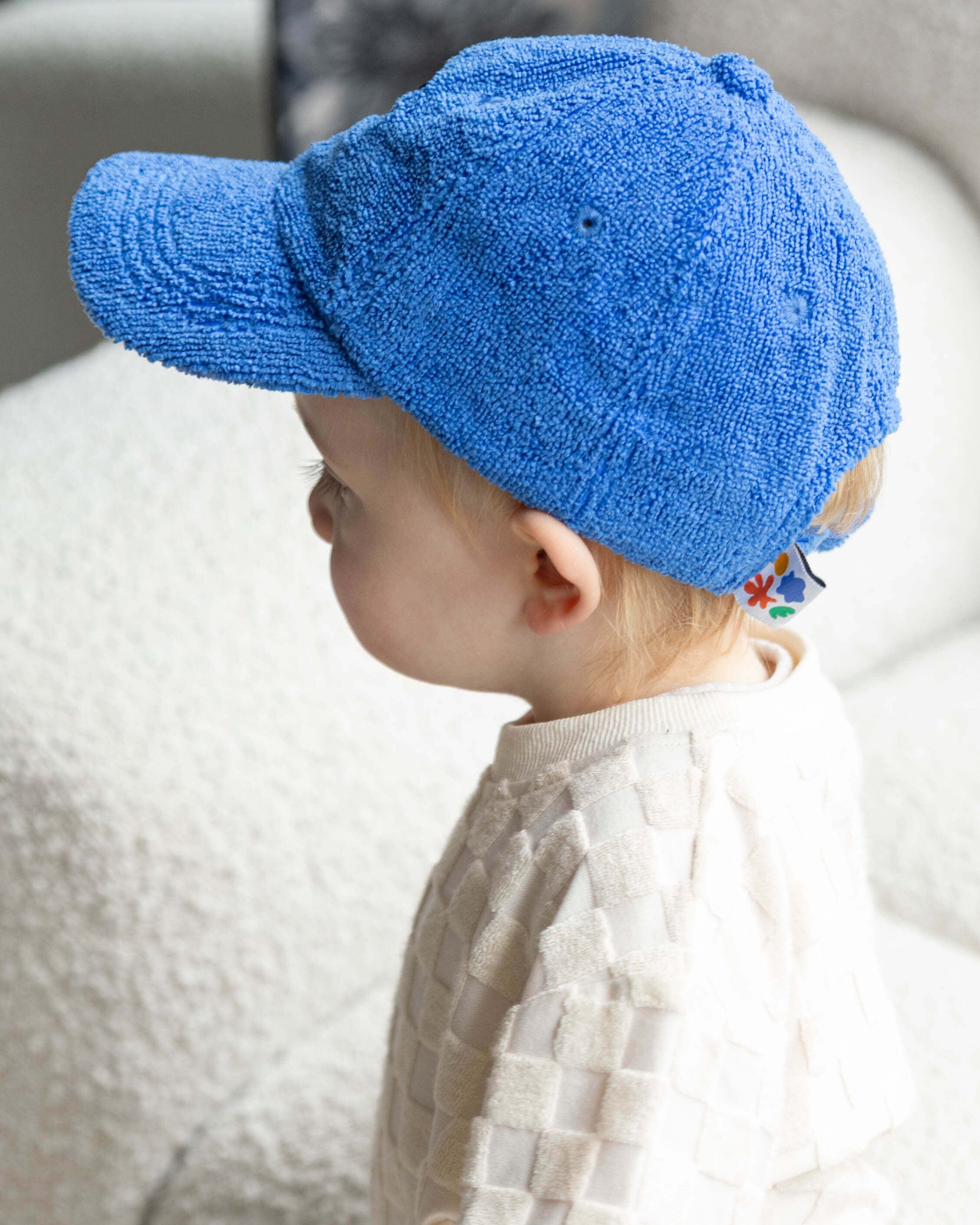 Child wearing a blue towel cap sitting on a textured surface