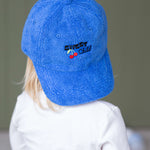 Child wearing a blue cap with a logo on a plain background