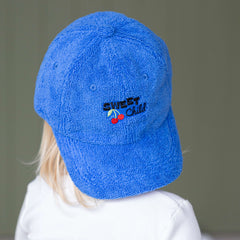Child wearing a blue cap with a logo on a plain background