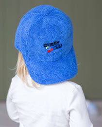 Child wearing a blue cap with a logo on a plain background