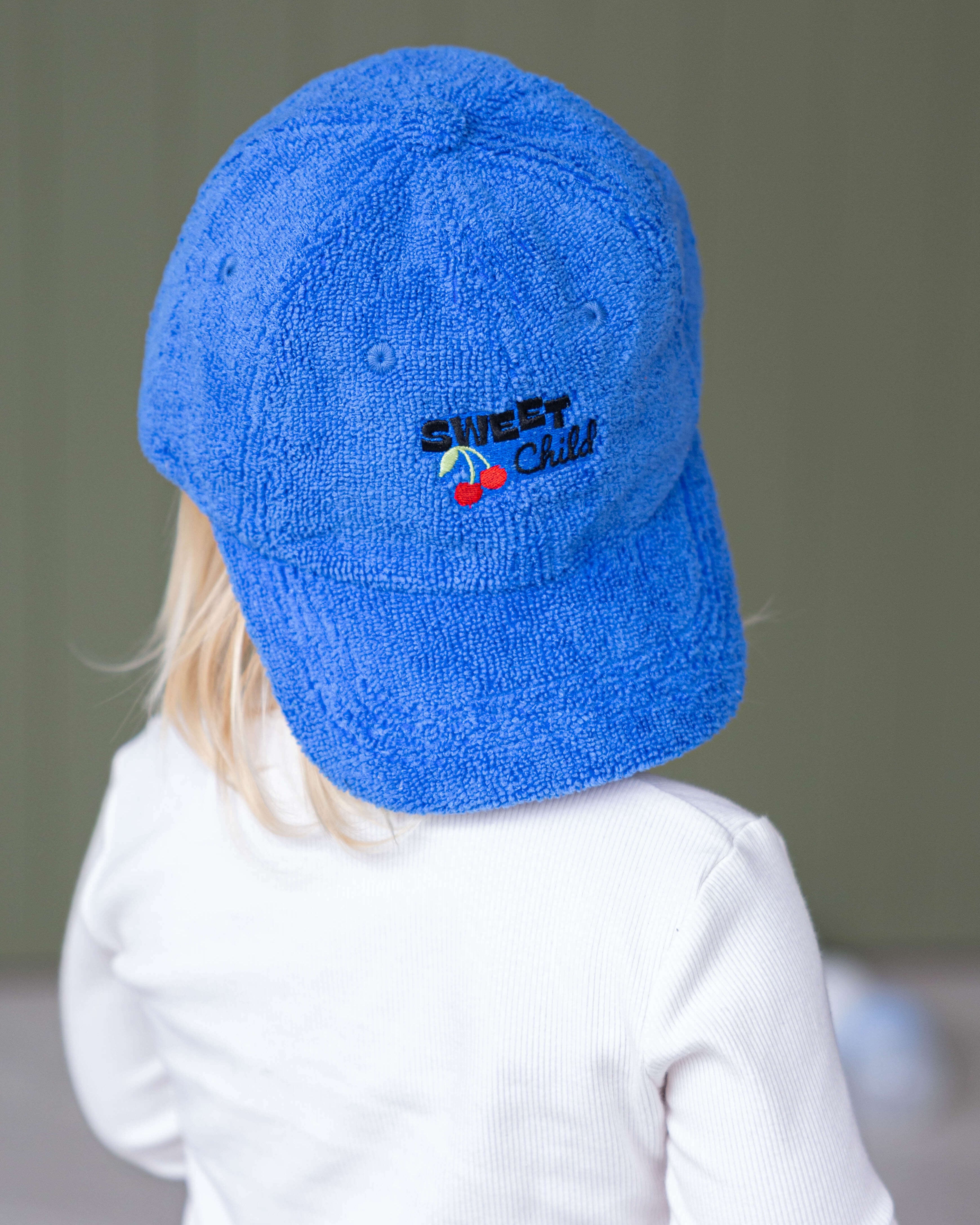 Child wearing a blue cap with a logo on a plain background