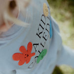 Close-up of a child's sweatshirt with text and colorful shapes, outdoors.