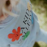Close-up of a child's sweatshirt with text and colorful shapes, outdoors.