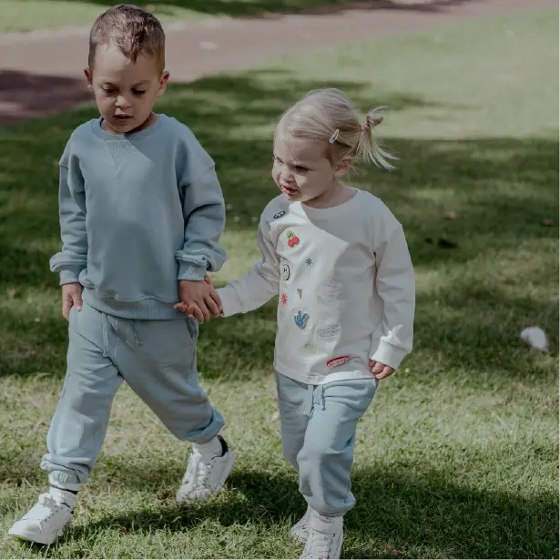 Two children holding hands on a grassy field