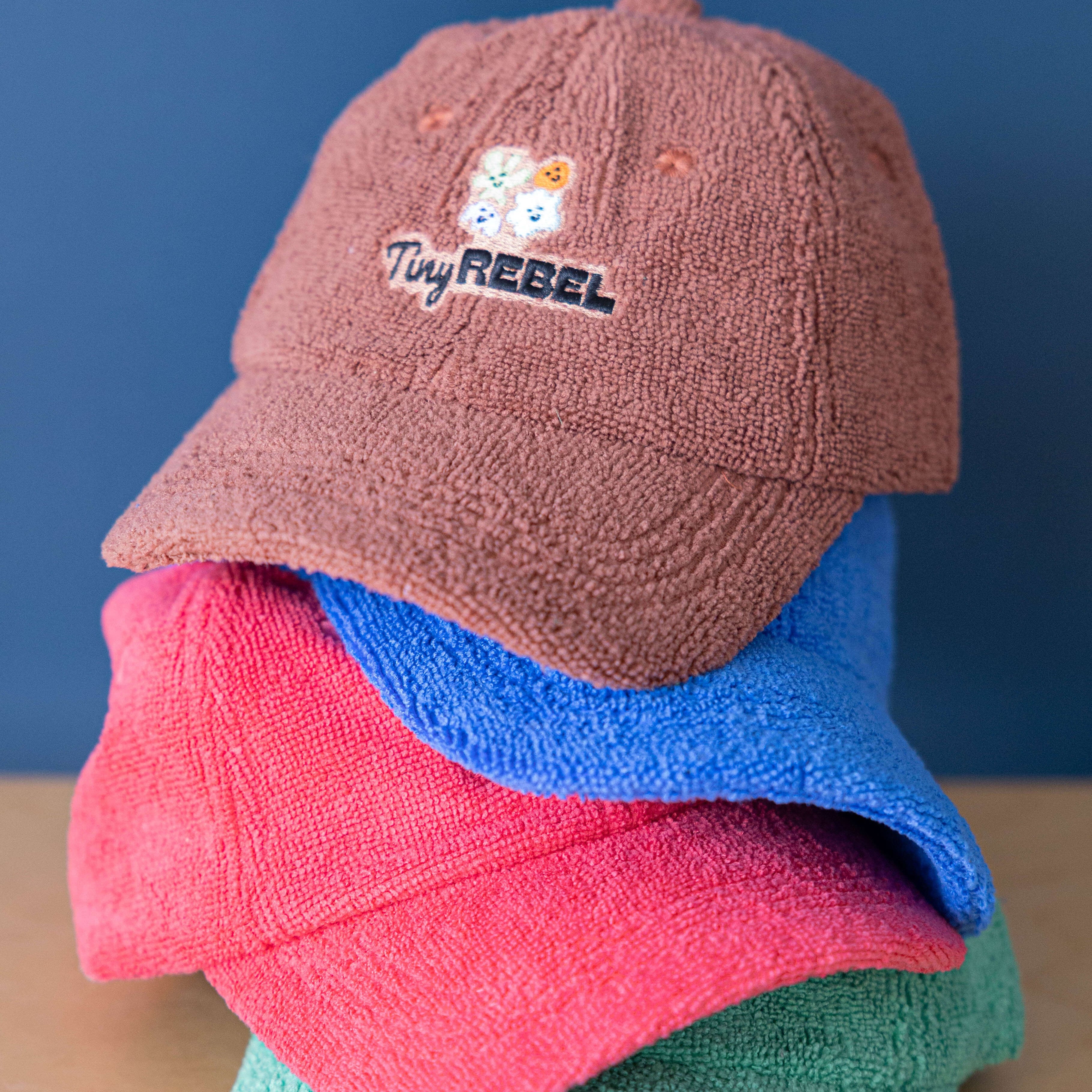 Stack of colorful caps with 'Tiny Rebel' logo on a blue background