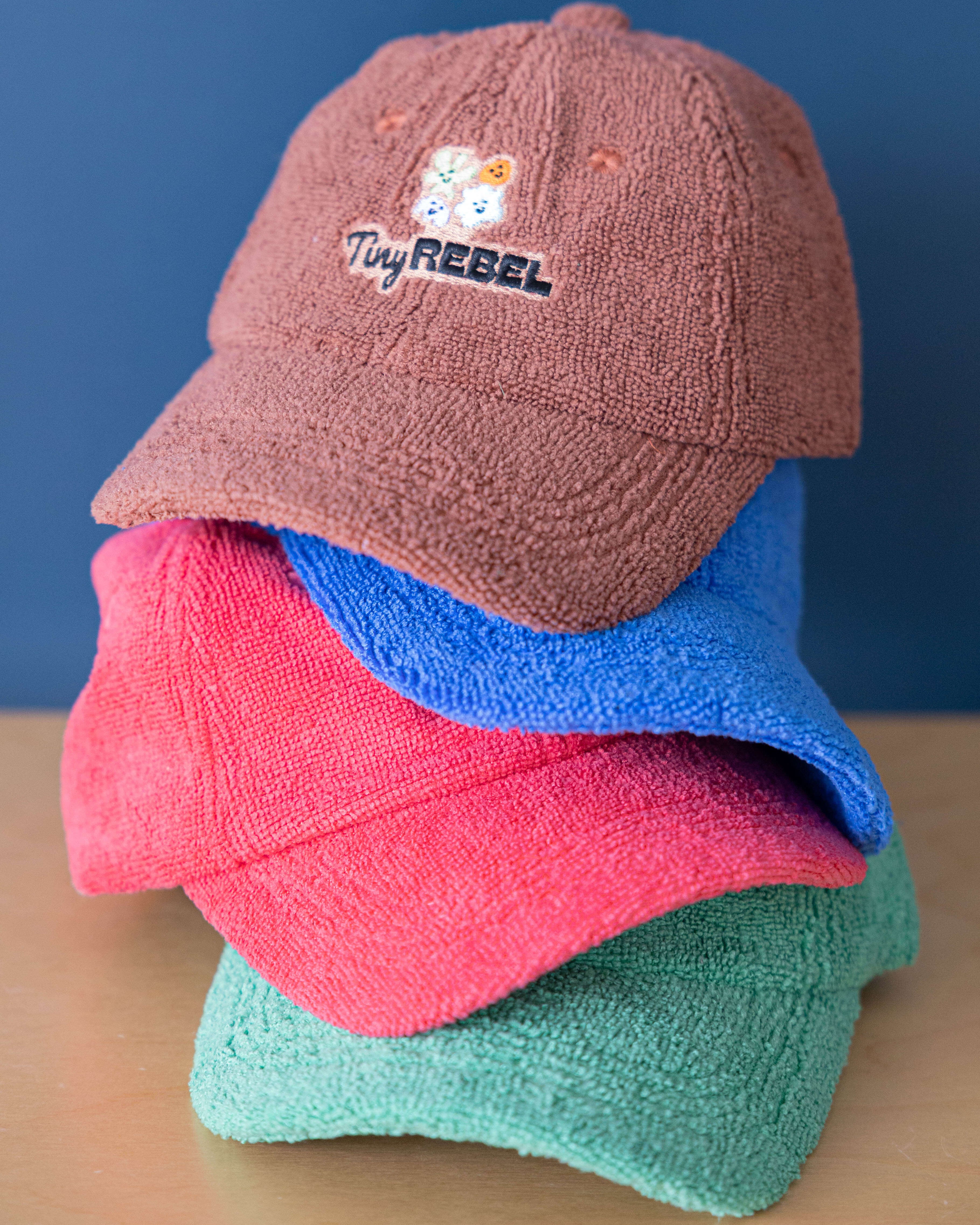 Stack of colorful caps with 'Tiny Rebel' logo on a blue background