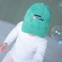 Child wearing a green towel with 'Mood: Mischief' text, surrounded by bubbles on a gray background