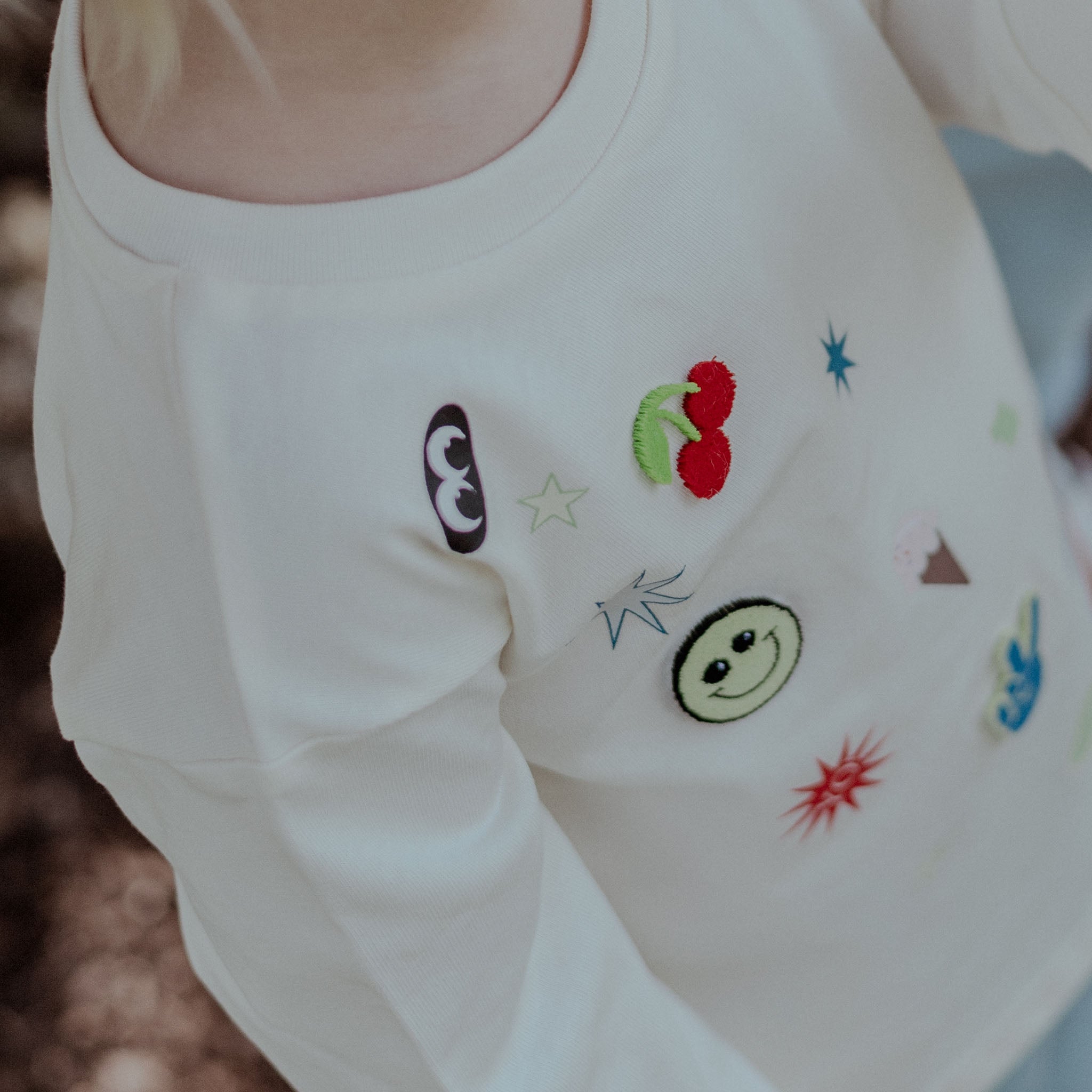 child wearing White shirt with colorful embroidered designs on a blurred background