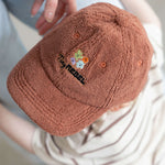 Brown textured cap with colorful embroidery worn by a toddler