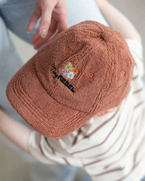 Brown textured cap with colorful embroidery worn by a toddler
