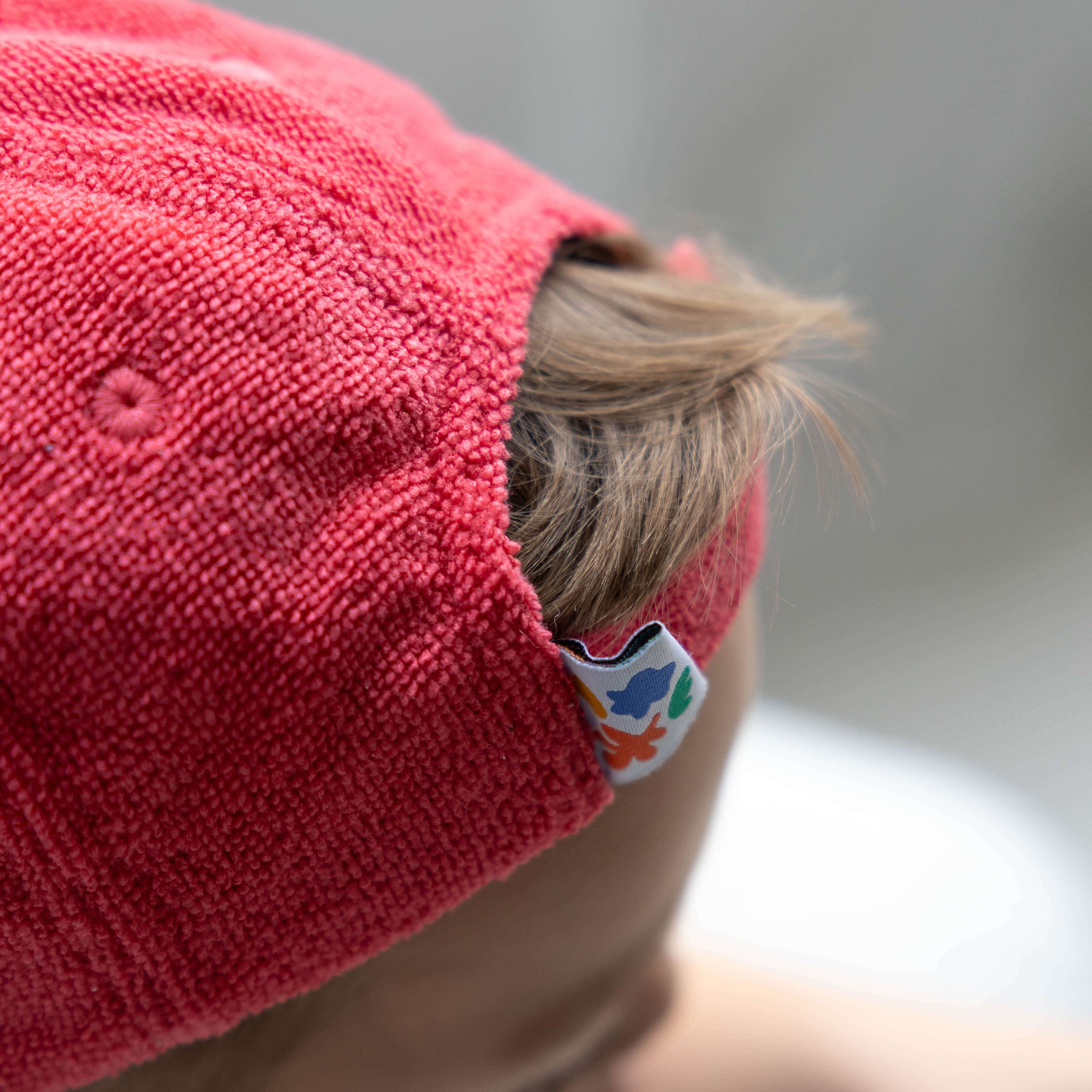 Close-up of a child wearing a red cap with a brand logo on a blurred background