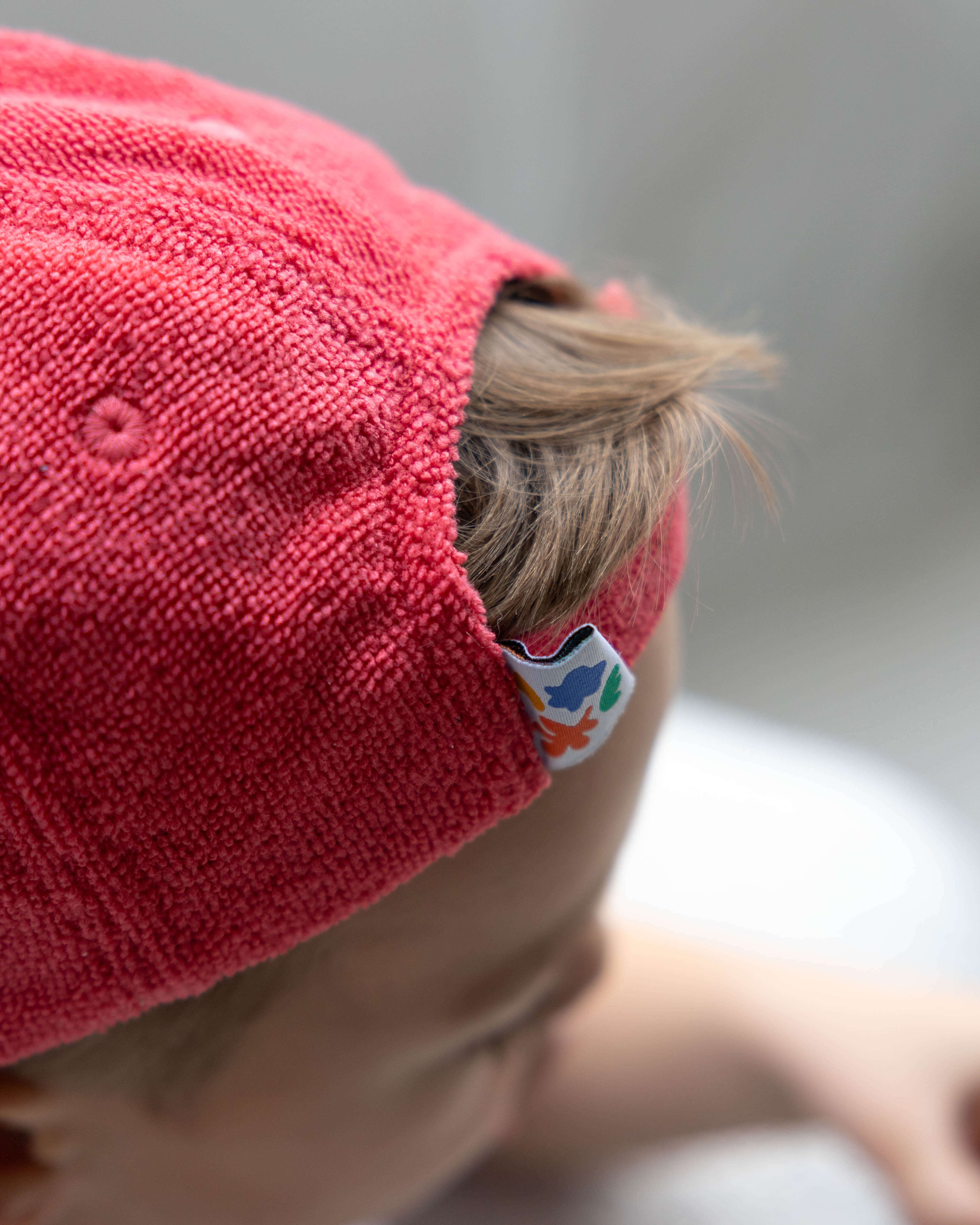 Close-up of a child wearing a red cap with a brand logo on a blurred background