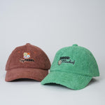Two textured baseball caps, one brown and one green, on a light gray background.