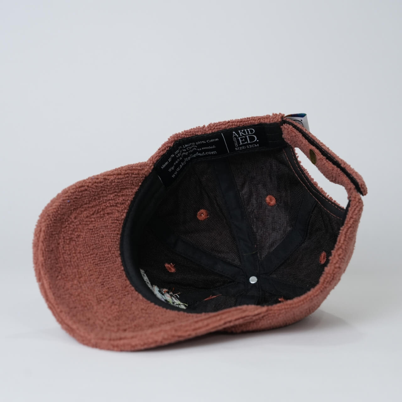 Brown cap with black interior and visible brand label on a light gray background