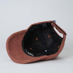 Brown cap with black interior and visible brand label on a light gray background