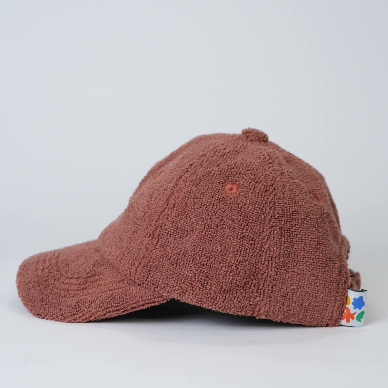 Brown textured cap with colorful tag on a light gray background