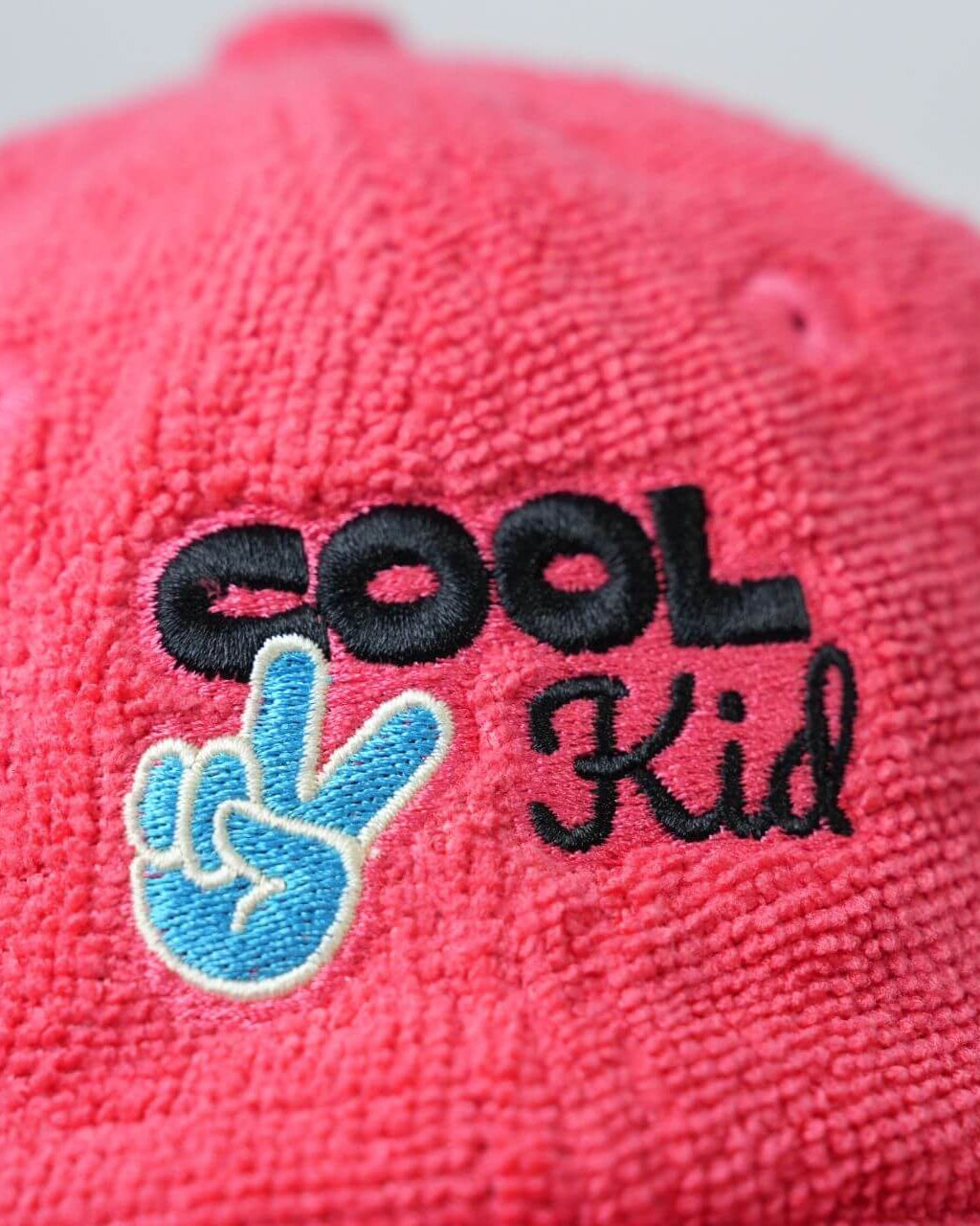Red cap with 'COOL Kid' text and hand gesture logo on a light gray background