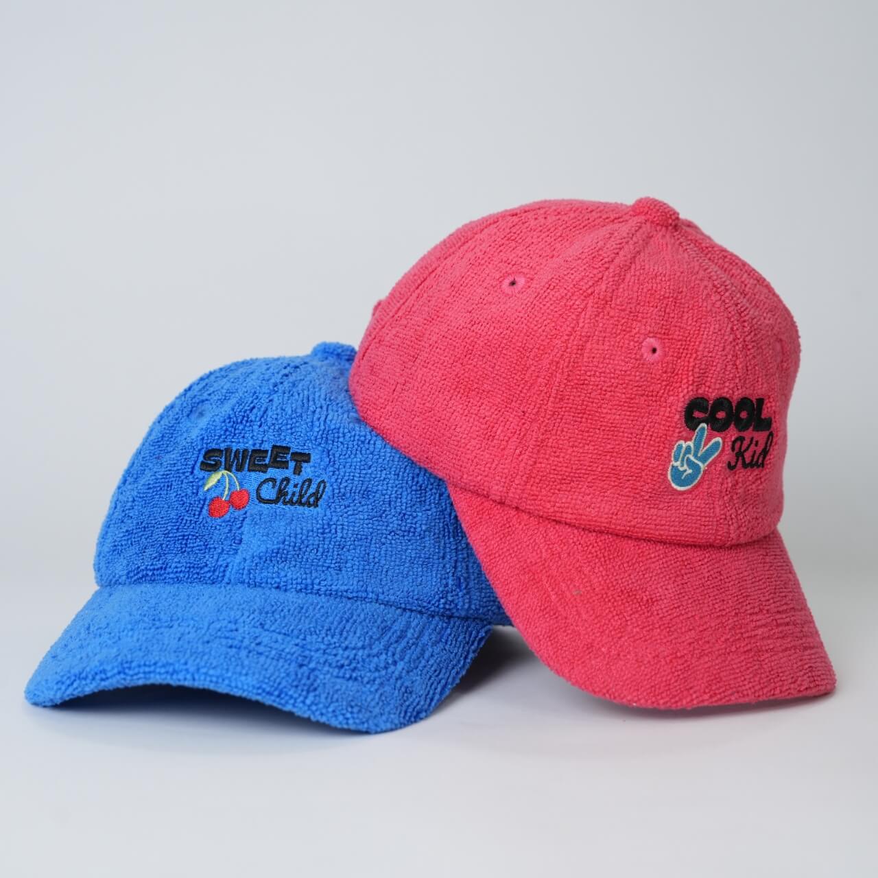 Blue and red caps with embroidered text on a light gray background