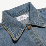Close-up of the denim jacket collar, neck label and brass button