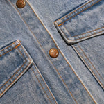 Close-up of the antique brass buttons and chest pocket on the kids denim jacket