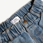 Close-up of the elasticated back waistband and brass button on the kids denim jeans