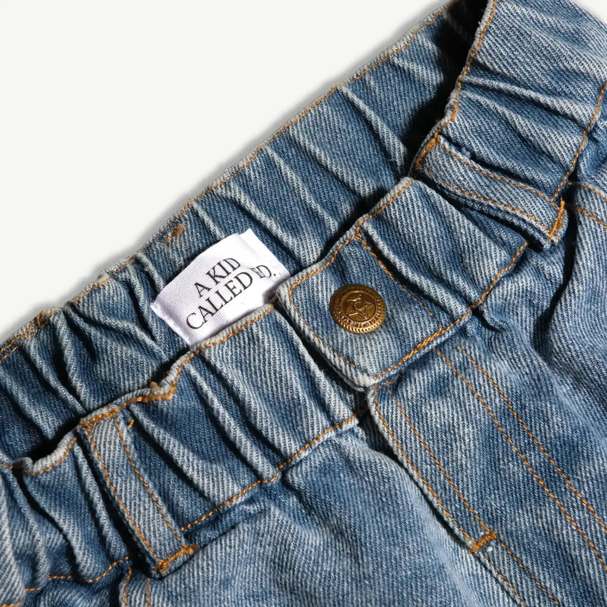 Close-up of the elasticated back waistband and brass button on the kids denim jeans