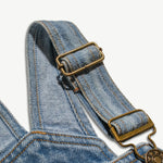 Close-up of the adjustable brass buckle on the kids denim overalls