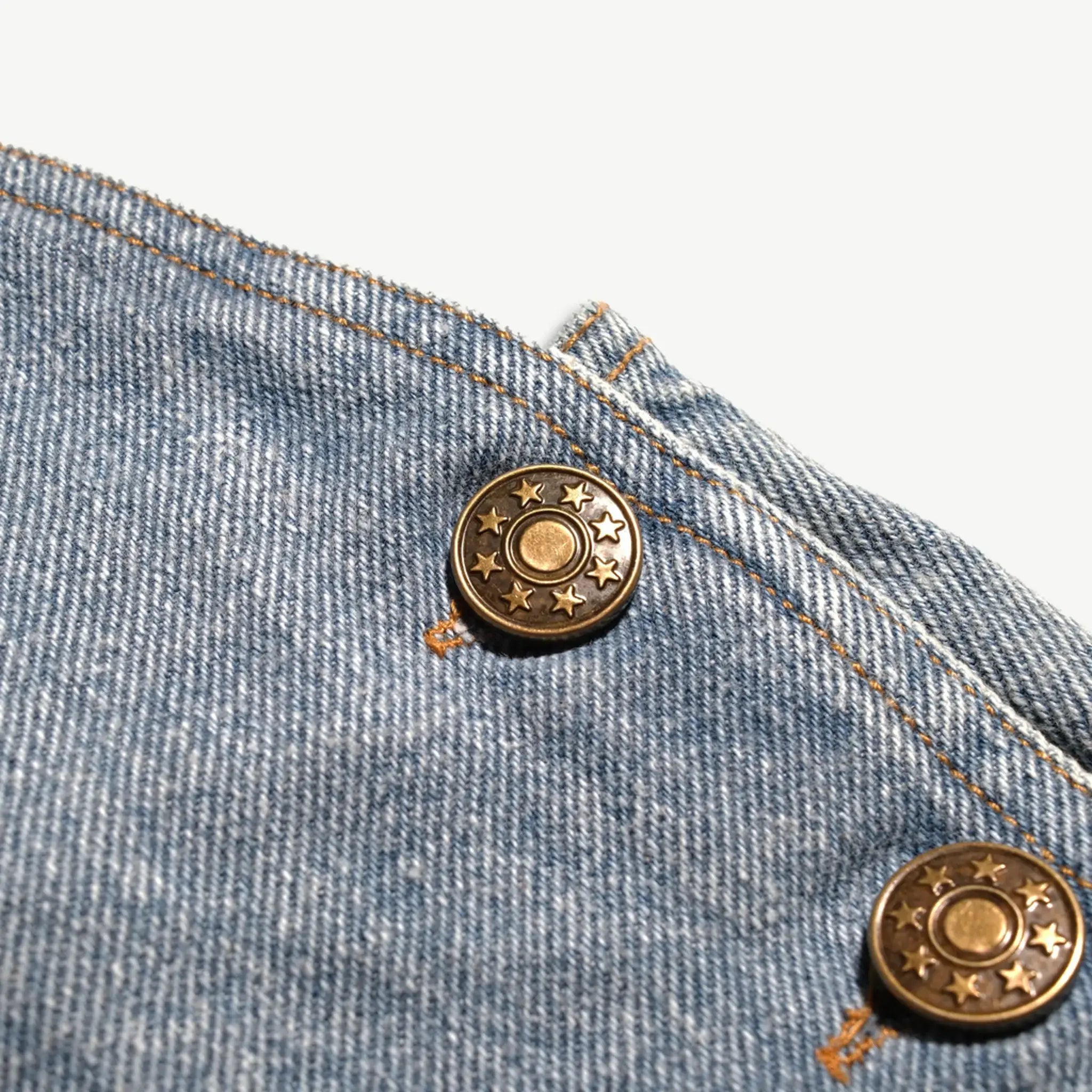 Close-up of the antique brass side buttons on the kids denim overalls