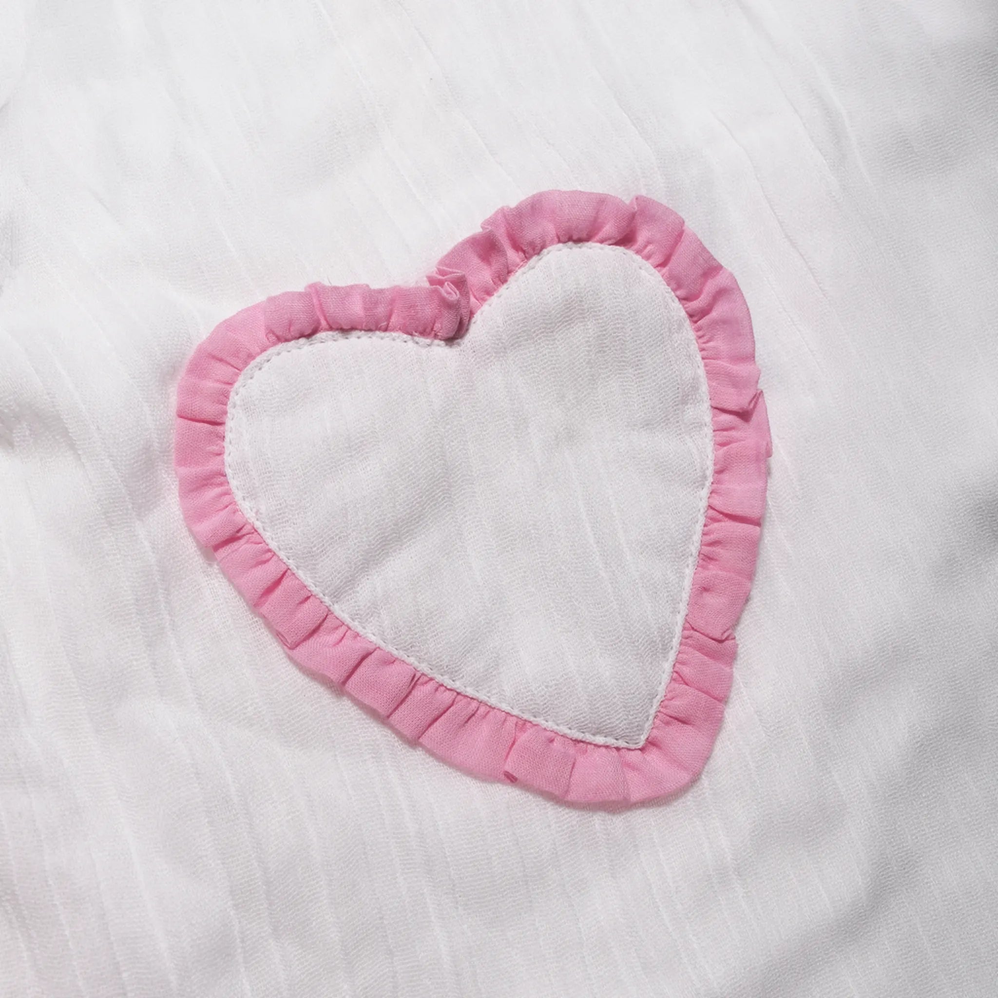 Close-up of the pink frilled heart pocket on the organic cotton muslin dress