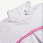 Close-up of the neckline frill and pink trim on the organic cotton muslin dress