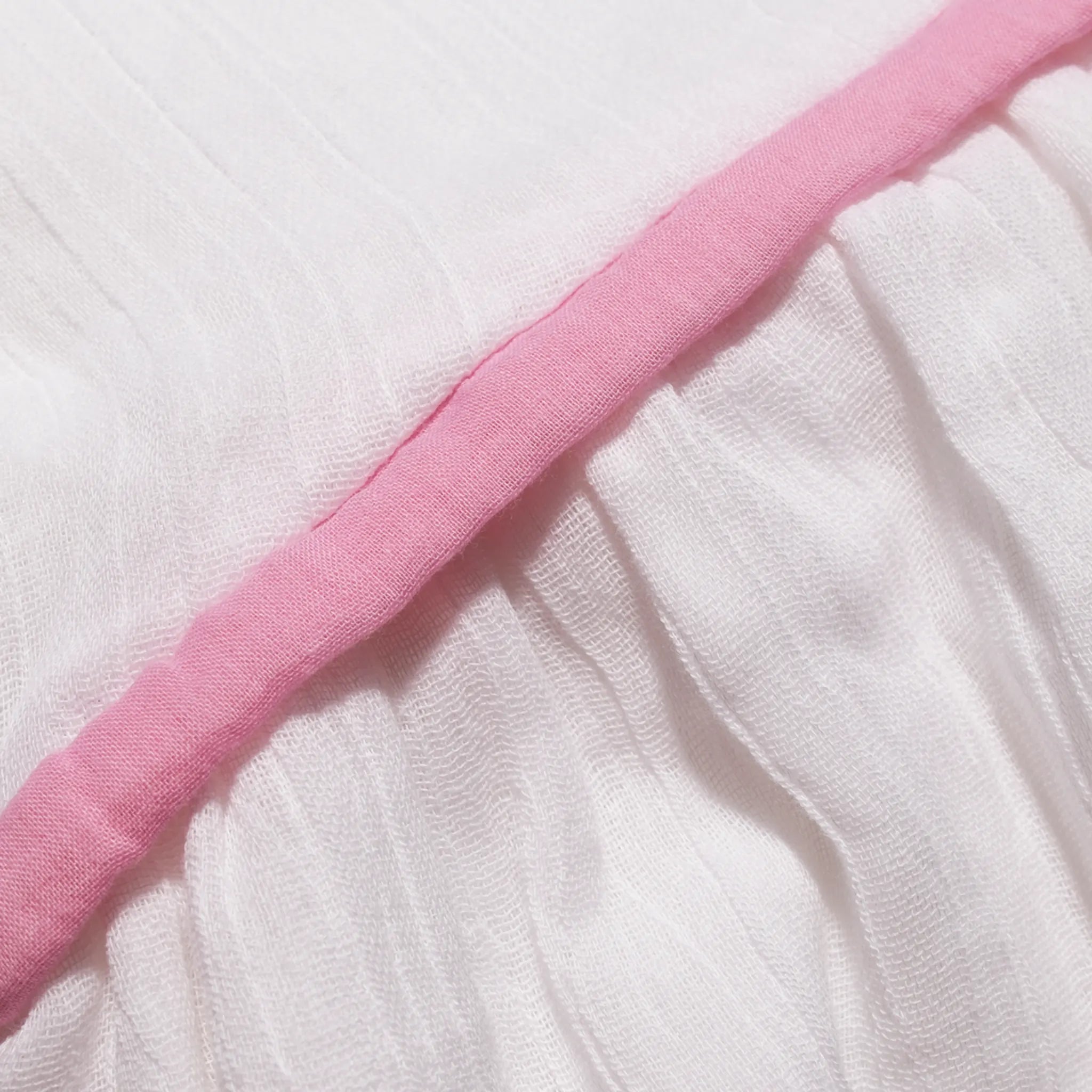 Close-up of the pink trim running through the organic cotton muslin dress