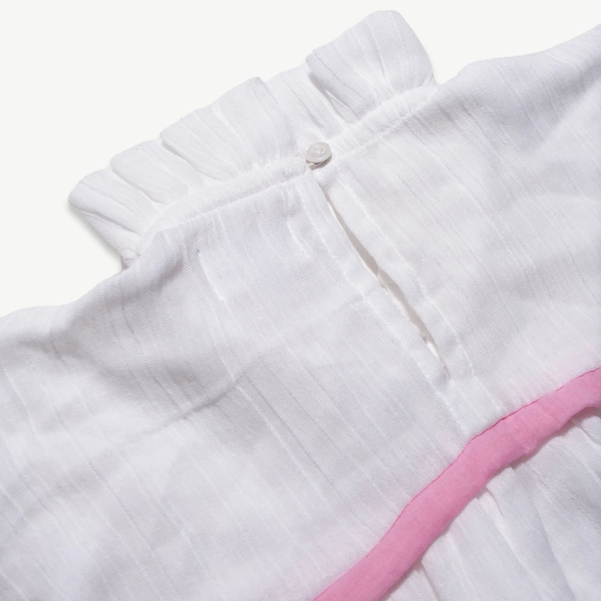 Close-up of the button placket and pink trim on the kids muslin dress